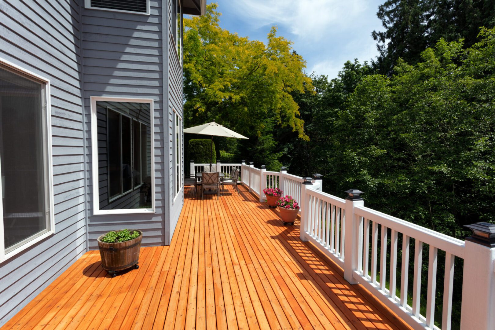 Wooden deck with chairs and potted plants.