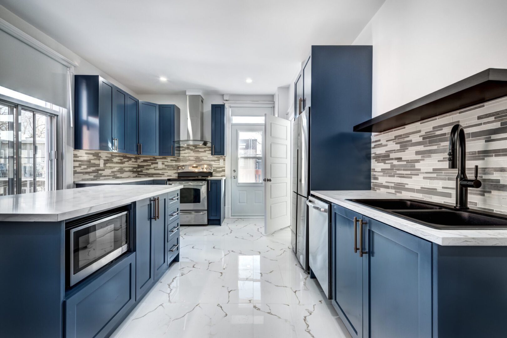 Modern kitchen with blue cabinets and marble floor.