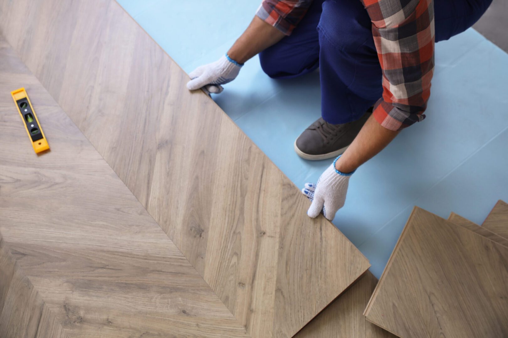 Person installing interlocking wood flooring tiles.