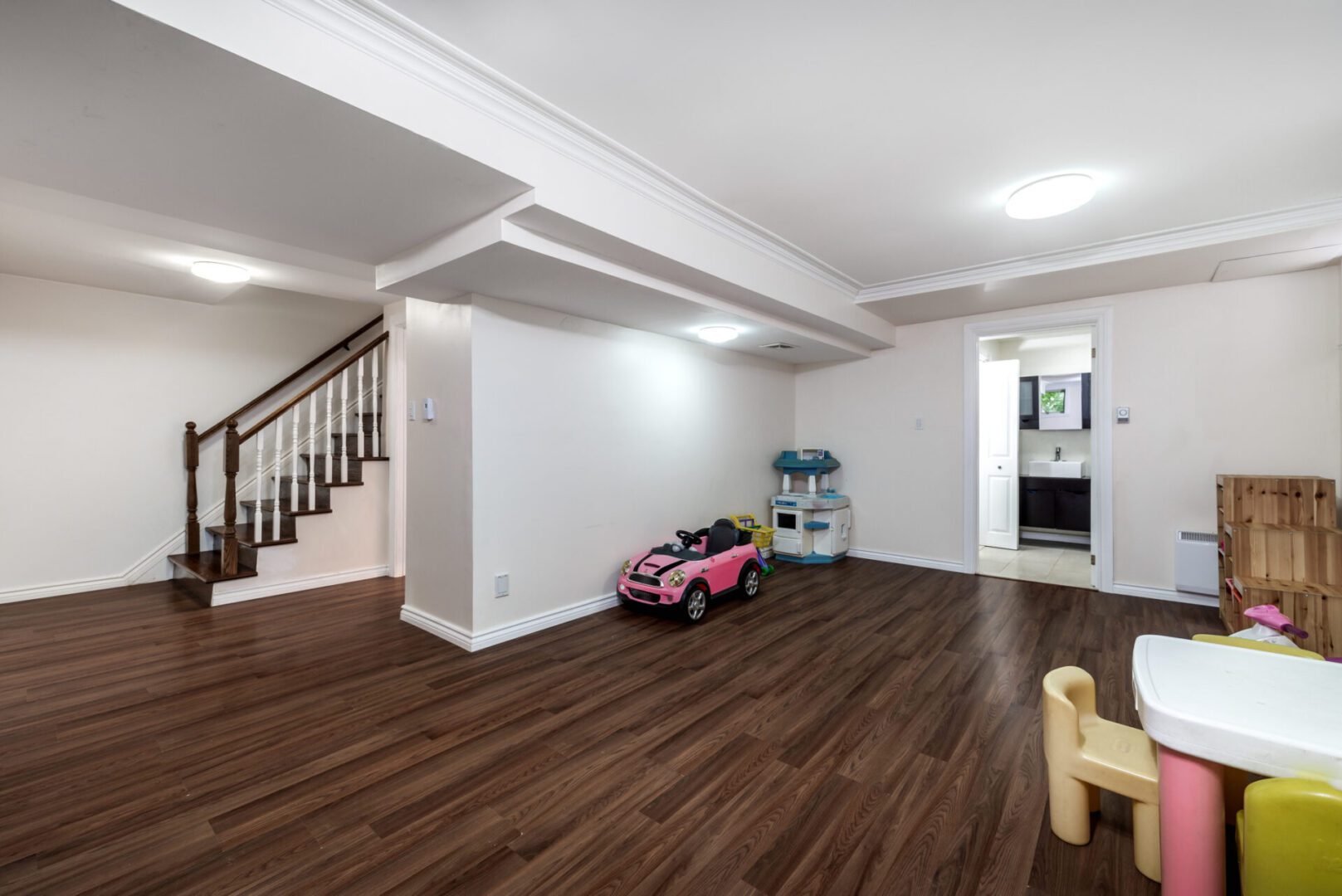 Basement playroom with toy car and furniture.