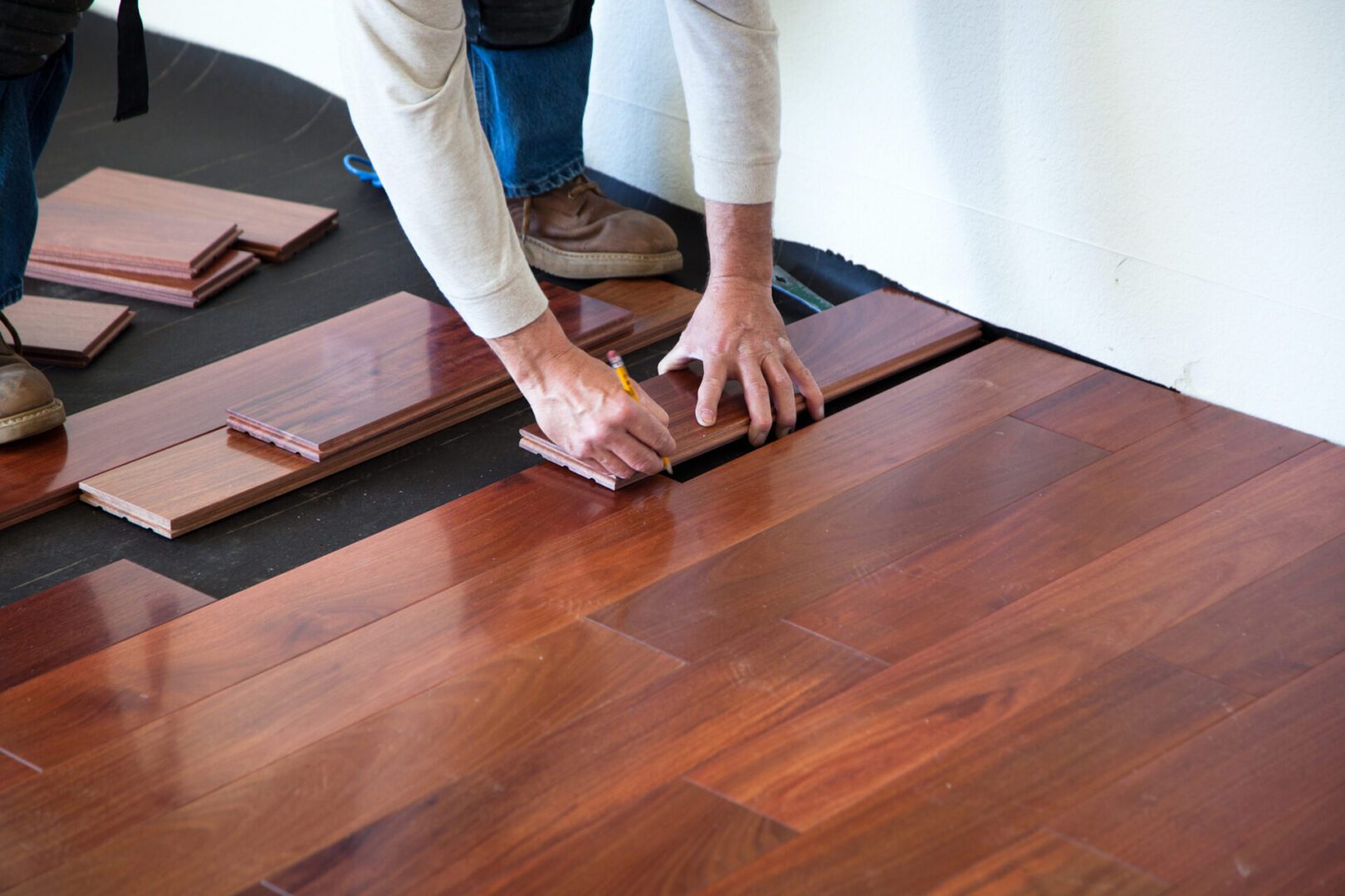 Installing wooden floor panels with tools.