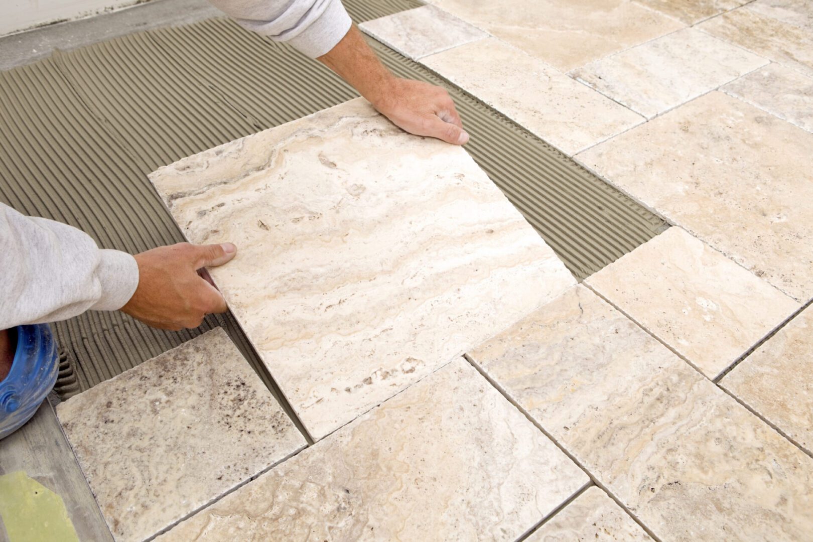 Laying a travertine tile on floor.