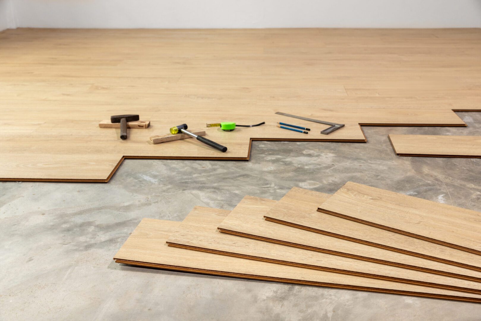 Wood flooring installation with tools on floor.