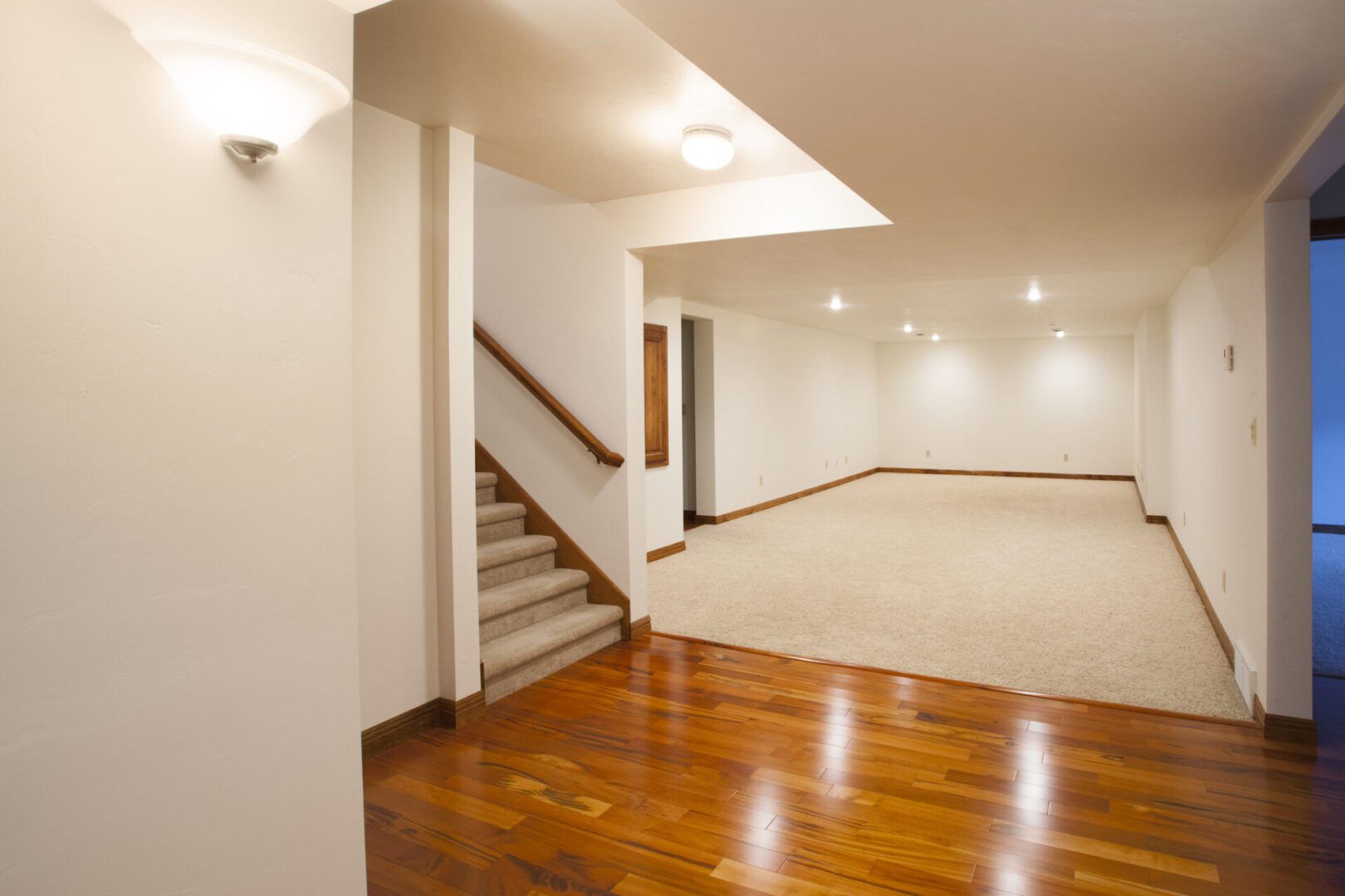 Basement room with stairs and wooden floor.