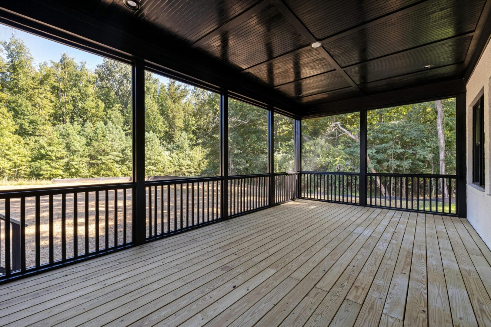 Screened porch with wooden floor and trees.
