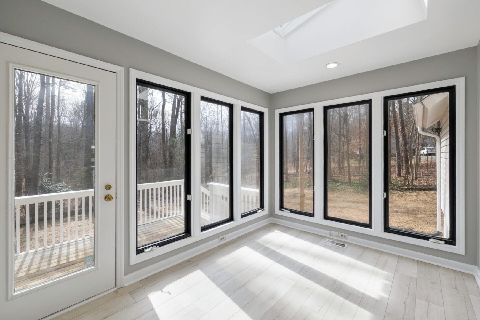 Bright sunroom with large windows and forest view.