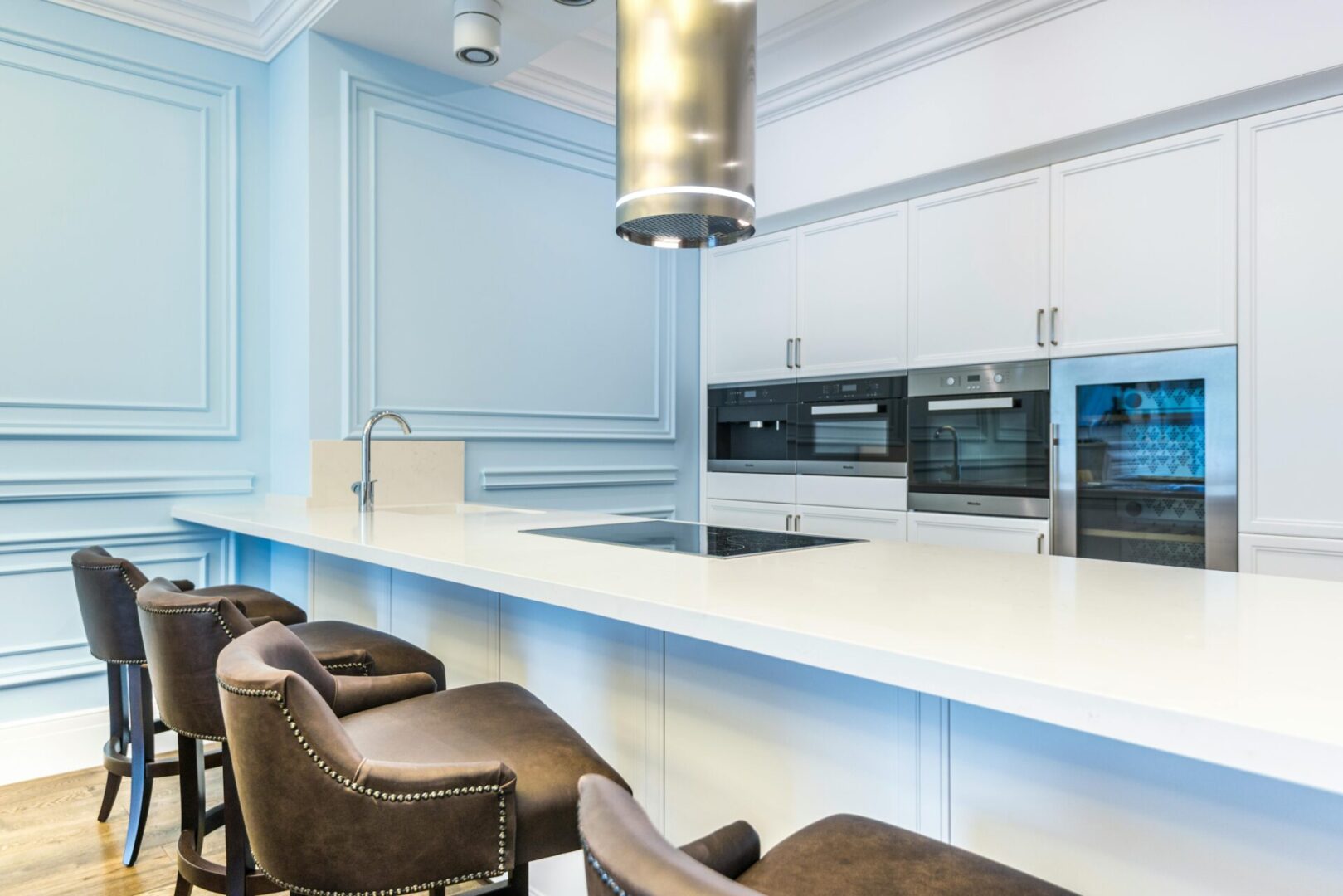 Modern kitchen with white countertops and chairs.
