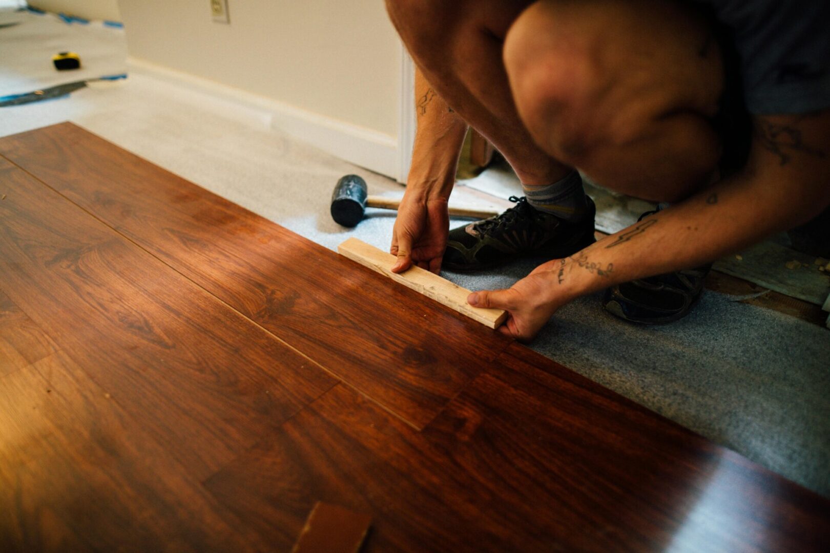Installing wooden flooring with measuring tool.