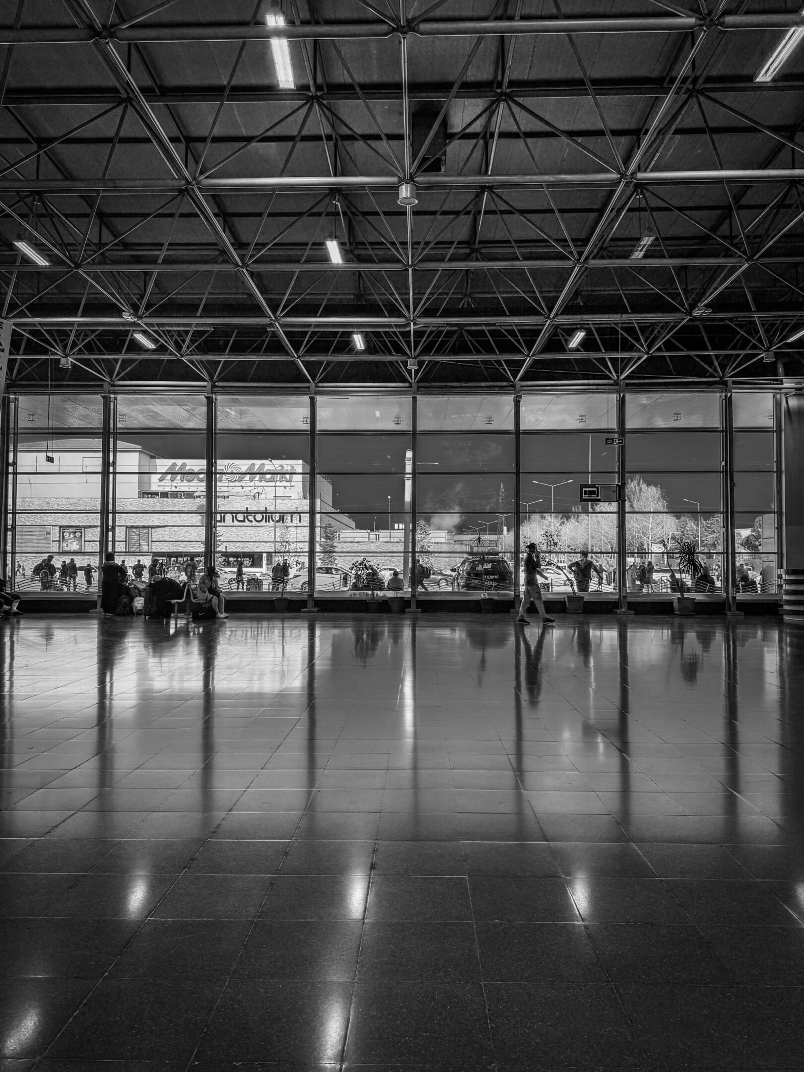 Airport terminal with large windows, black-and-white.